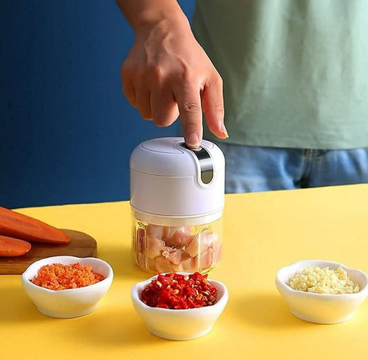 Hand using a small handheld food chopper with ingredients on a yellow surface