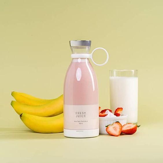 Pink juice bottle with bananas, a glass of milk, and strawberries on a light yellow background