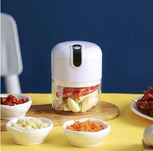 Handheld food chopper with chopped ingredients on a yellow table against a blue background