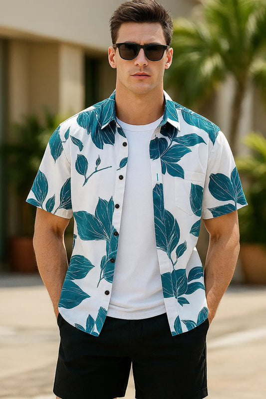 Man wearing a white shirt with green leaf pattern and sunglasses outdoors.